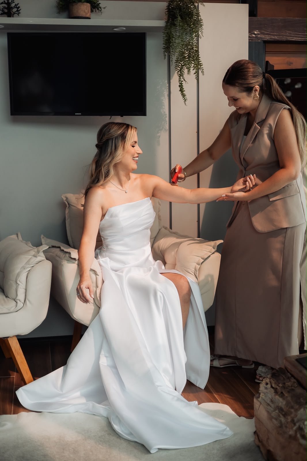 Noiva sentada com o vestido enquanto recebe ajuda